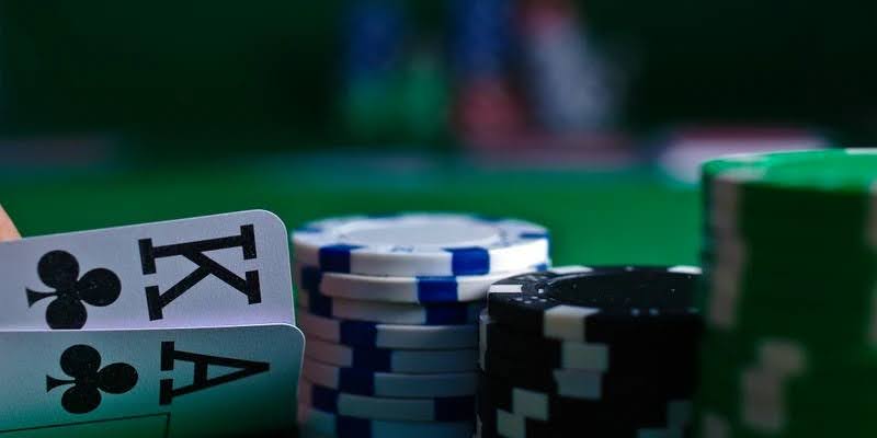 Close-up of a professional dealer distributing playing cards from a multi-deck shoe on a green felt table.